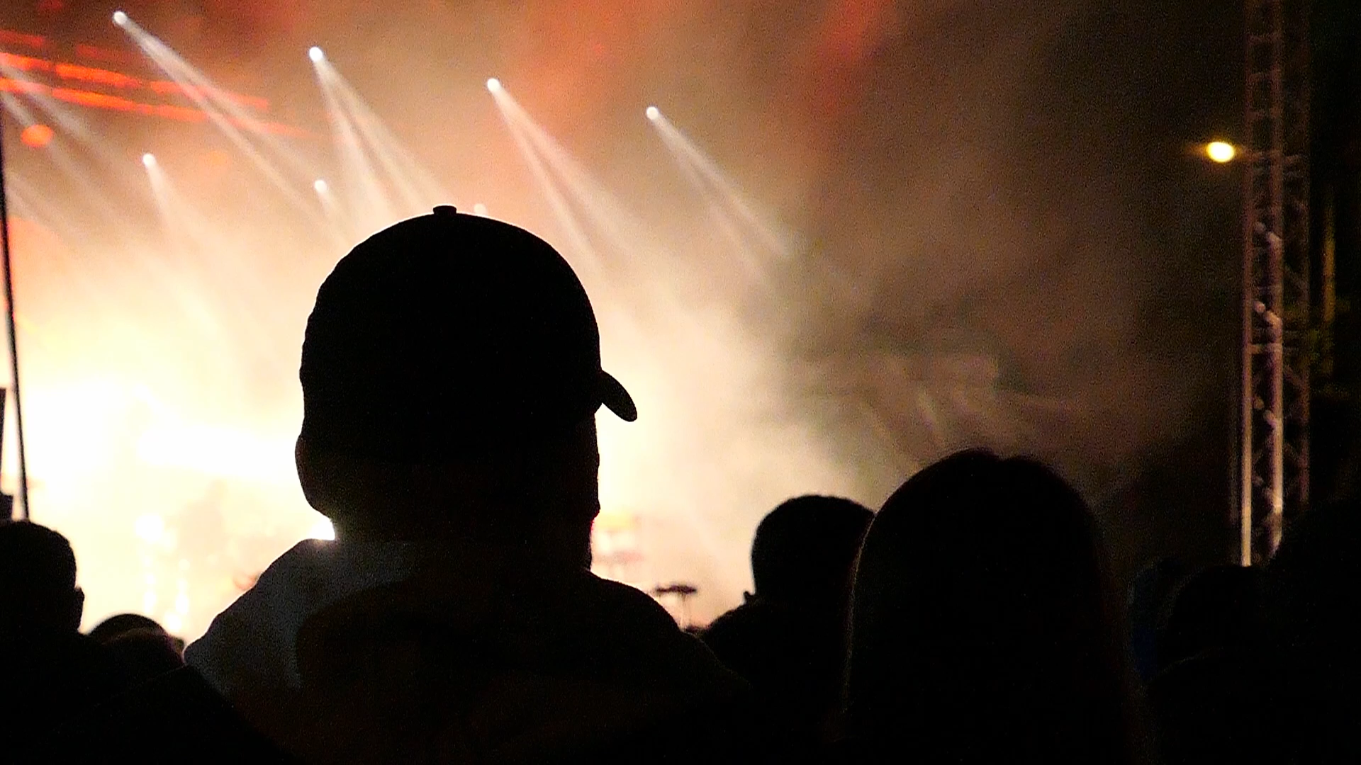 Público observando un concierto con luces intensas y humo escénico desde la perspectiva de la multitud