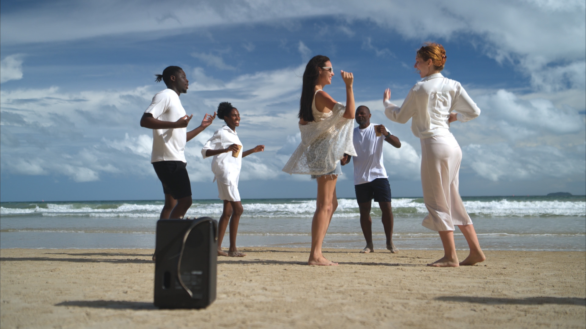 Grupo de personas bailando en la playa junto al mar.