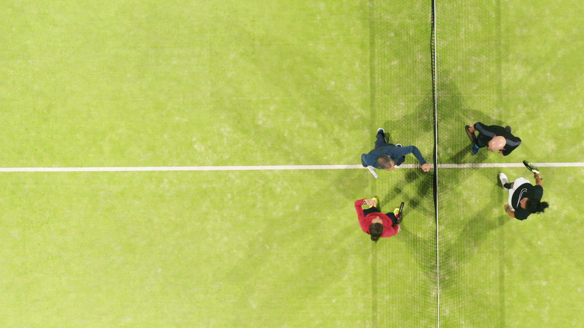 Vista aérea de una pista de pádel con varios jugadores junto a la red